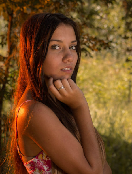 Image of pensive girl in woods with a sunset glow against her back